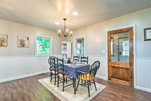A dining room with a round table, chairs, a chandelier, and a wooden door. - Beautifully Restored Farmhouse in Marshall! (Marshall)
