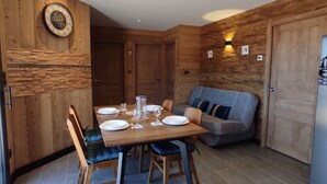 Un coin repas avec une table en bois dressée pour quatre personnes, entourée de chaises dotées de coussins bleus.