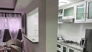 Una cocina moderna con electrodomésticos de acero inoxidable, gabinetes blancos y un comedor con sillas y una mesa.