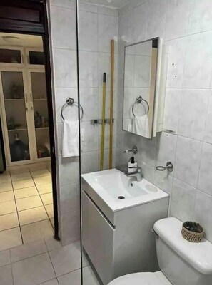 A bathroom with a white sink, a toilet, a glass shower enclosure, and a mirror above the sink. - ,self check-in,beautiful, céntric, first floor. (Santiago De Los Caballeros)