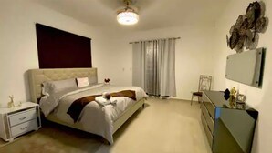 Un dormitorio con cama, mesita de noche, cómoda y espejo en la pared.