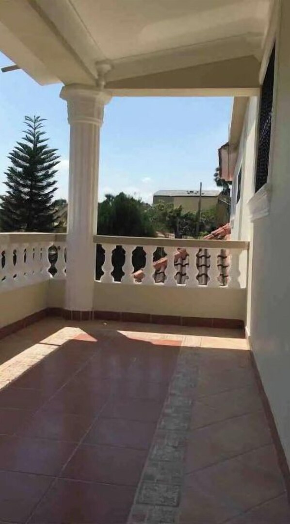 Un balcon doté d’un sol carrelé et d’une balustrade blanche agrémentée d’éléments décoratifs.