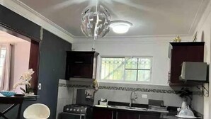 Una cocina con armarios oscuros, una estufa a gas, un lavamanos y una lámpara moderna.