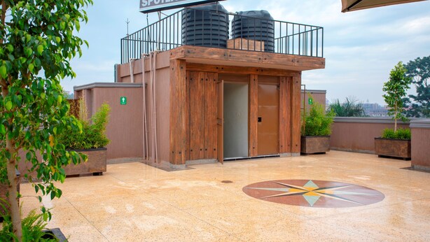 A motel with a wooden facade, a sign reading "SPOTLIGHT MOTEL," and a tiled floor with a geometric design. - Spotlight Motel (Kampala)