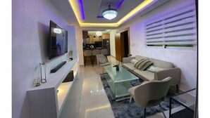 A modern living room with a flat-screen TV, a glass coffee table, and a beige sofa. - Apartment with jacuzzi (Santiago De Los Caballeros)