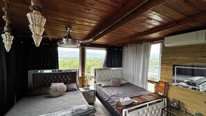 A bedroom with two beds, a wooden ceiling, a large window with a view, and a mounted TV. - Apartment with jacuzzi (Santiago De Los Caballeros)