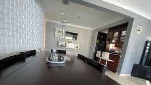 Een moderne eethoek met een donker houten tafel, witte stoelen en een decoratief bord met bolvormige objecten.