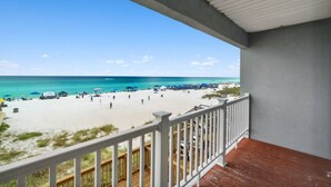A balcony with a view of a beach, wooden deck, and a railing.