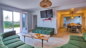 Una sala de estar moderna con sofás verdes, una mesa de centro de madera y un comedor con una mesa y sillas.