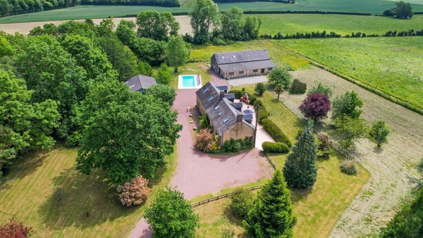 Vista aérea de una propiedad con una casa grande, piscina y campos circundantes.