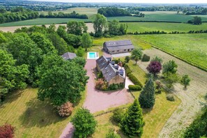 Vista aérea de una propiedad con una casa grande, piscina y campos circundantes.