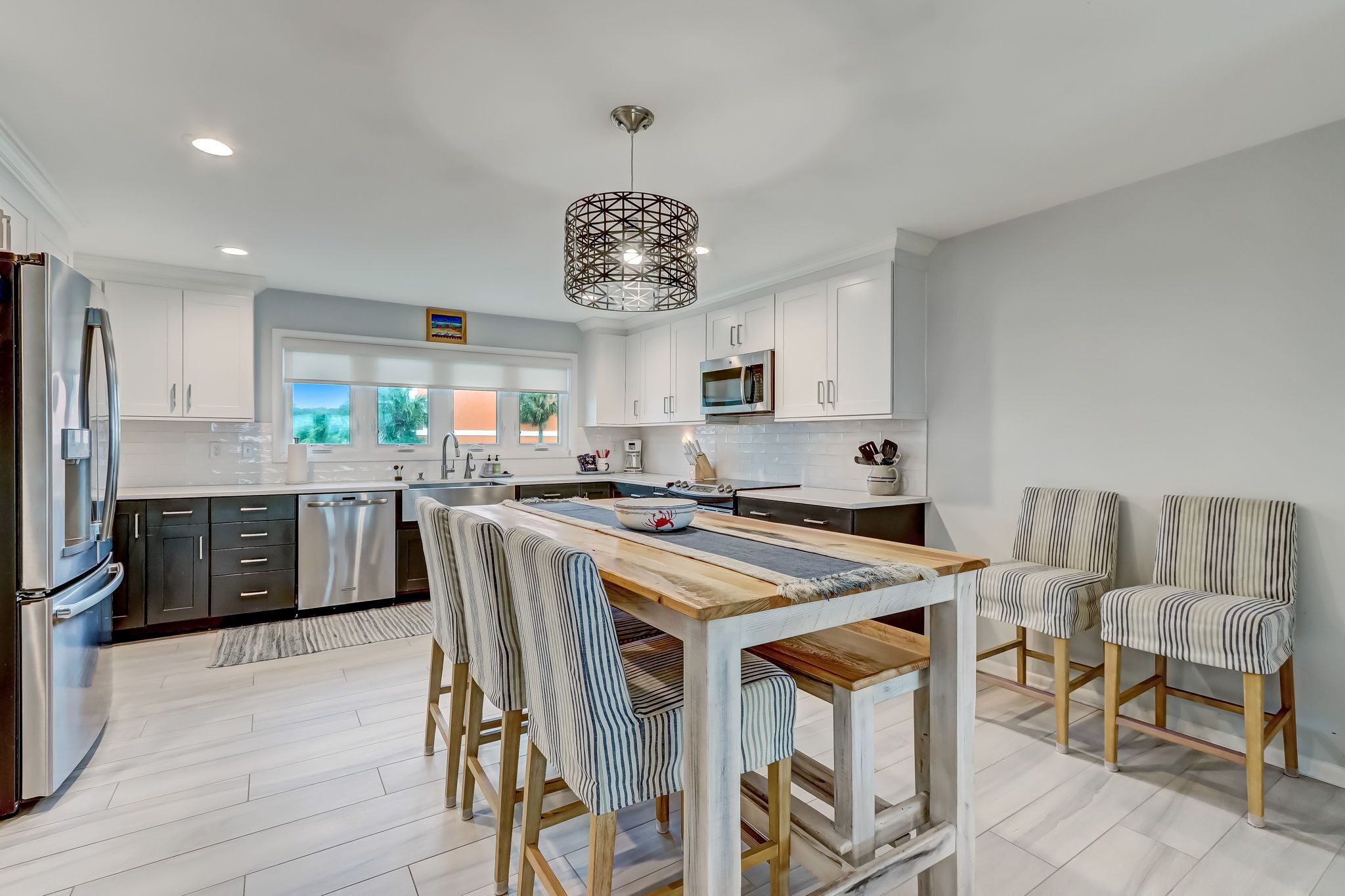 Una cocina moderna con armarios blancos, electrodomésticos de acero inoxidable y una mesa de comedor de madera con sillas a rayas.