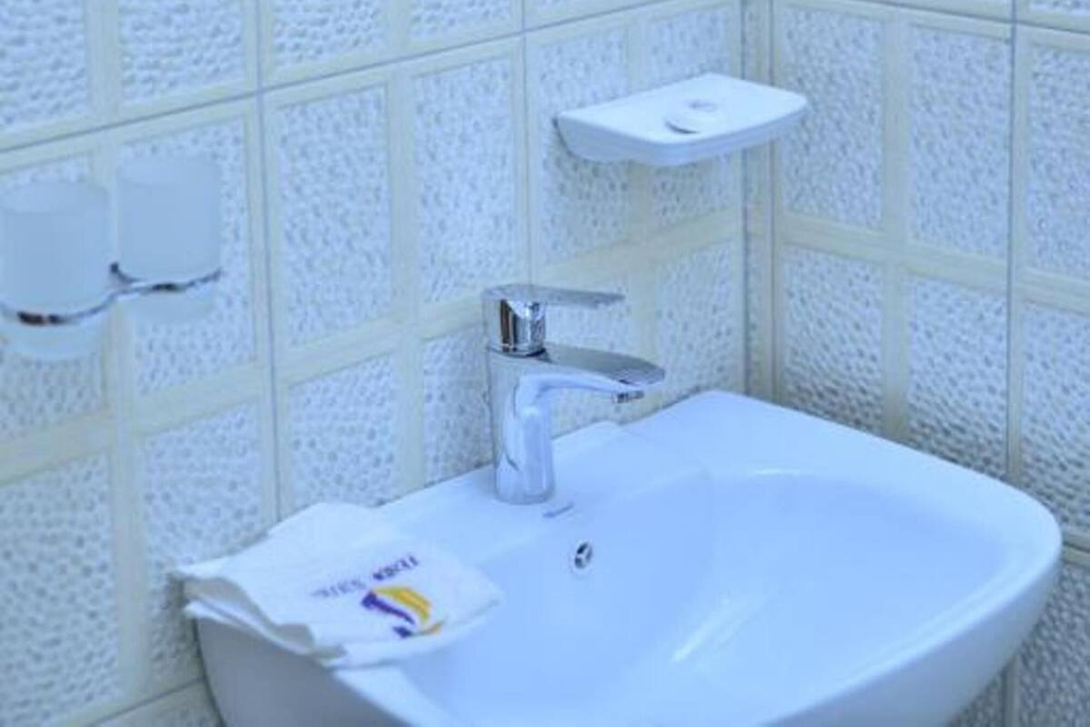A bathroom with a white sink, a mirror, and a soap dispenser on the wall.