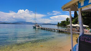 A pier extending into a calm lake with a sailboat docked at the end. - Eros Sea View in Kentroma (Corfu)