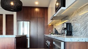 A modern kitchen with dark wood cabinets, stainless steel appliances, and a marble backsplash. - New! Slick designer apARTtment with bay views. (Cabo San Lucas)