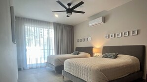 A hotel room with two beds, a ceiling fan, an air conditioning unit, and a window with curtains. - New! Slick designer apARTtment with bay views. (Cabo San Lucas)