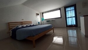 A bedroom with a bed, a window, and a ceiling fan.