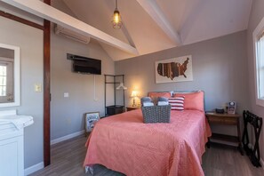 Un dormitorio con una cama, una lámpara, un televisor montado en la pared y un mapa de los Estados Unidos.