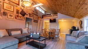 A cozy living room with a loft bed, wooden ceiling, and various framed pictures on the walls. - The Hideaway, lake views & access sleeps 8 Now featuring AC Wi-FI and TV (Alton)