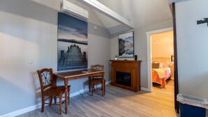 A room with a dining table, chairs, a fireplace, and a bed with a view of the outdoors. - Lake View Cabin in Alton Bay Now featuring Lake Access, AC/ TV/ WiFi (Alton)