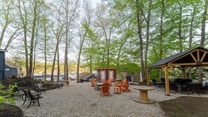 An outdoor seating area with tables and chairs, surrounded by trees and a gravel path. - Cabin for two with lake views & access Now featuring AC Wi-FI and TV (Alton)