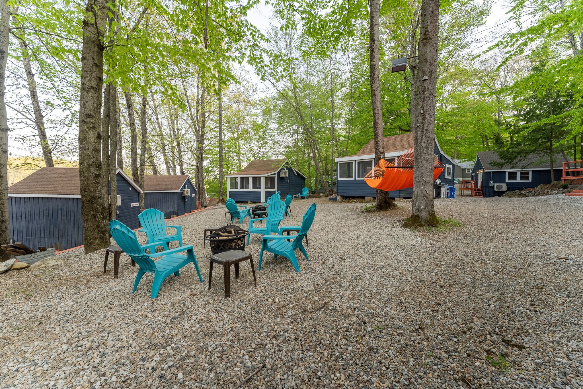 Un terrain de camping doté de plusieurs cabanes, d’un espace extérieur aménagé pour s’asseoir et d’un foyer.