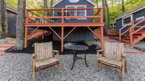 Une cabane avec une terrasse, deux chaises en bois et une petite table.