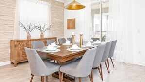 A modern dining room with a wooden table set for six, grey upholstered chairs, and a gold pendant light. - Super luxury home, private pool, premium location (Kissimmee)