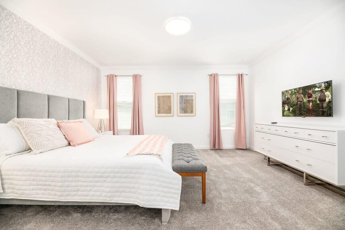 A bedroom with a bed, a bench, a dresser, and a painting on the wall.