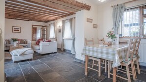 Una sala de estar acogedora con chimenea, un comedor con mesa y sillas, y una cocina visible al fondo.