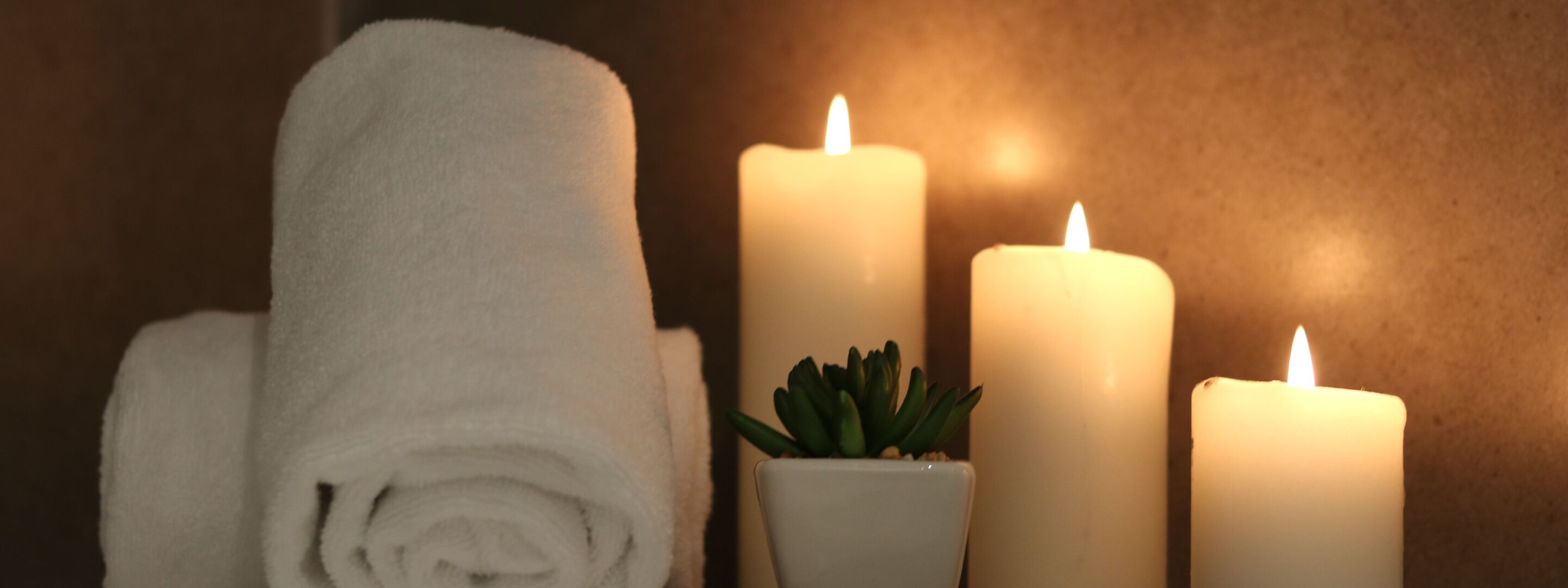 A towel, three candles, and a small potted plant.