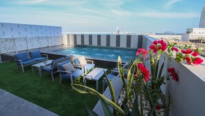 A rooftop pool area with a view of the city skyline, including a bridge. - The Seven Hotel (Manama)