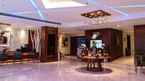 A modern lobby with a reception desk, seating area, and a decorative centerpiece. - The Seven Hotel (Manama)
