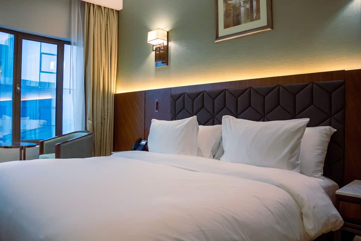 A hotel room with a large bed, a bedside table, a phone, and a window with curtains.