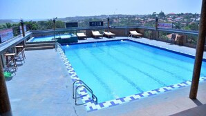 Una piscina en la azotea con sillones de descanso y vistas del paisaje circundante.