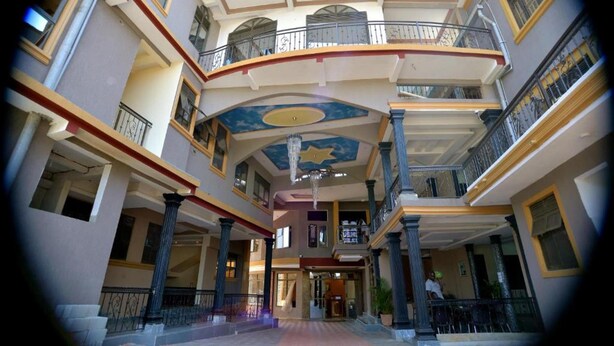 Un atrio de varios niveles con balcones, una escalera central y un techo decorativo.