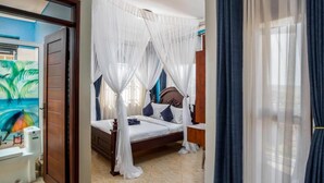 Un dormitorio con una cama, una mesita de noche y un ventanal con cortinas.