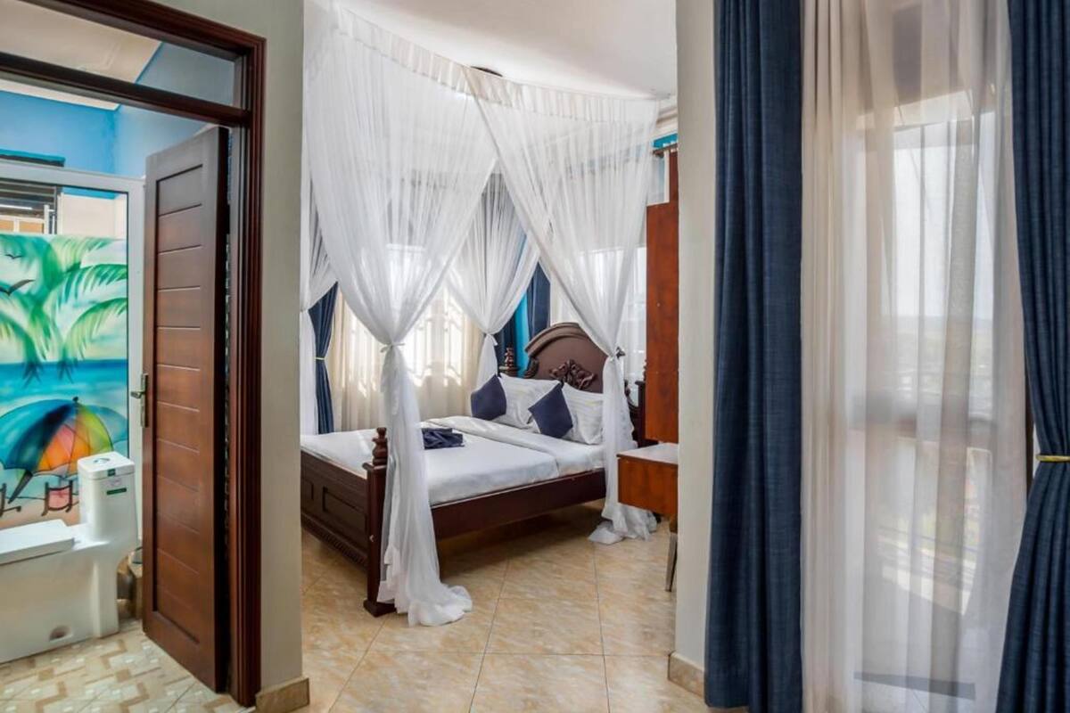 Une chambre à coucher avec un lit, une table de chevet et une fenêtre avec des rideaux.
