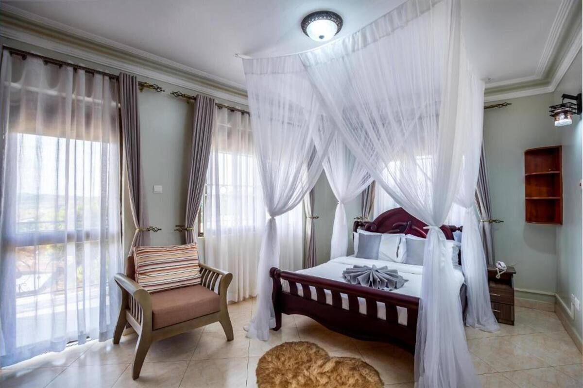 Une chambre à coucher avec un lit sous un dais, une chaise et un petit tapis.