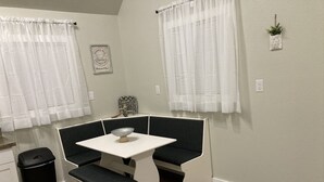 Una pequeña kitchenette con una encimera blanca, un cubo de basura negro y un lavabo blanco.