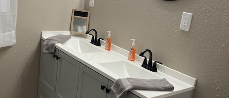 A bathroom with a double sink, two round mirrors, and a towel rack.