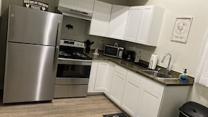 Una cocina moderna con armarios blancos, electrodomésticos de acero inoxidable y un tapete de estilo rústico.