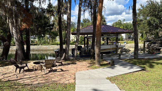 Un pabellón con zona de estar cubierta, una fogata y mobiliario de exterior.