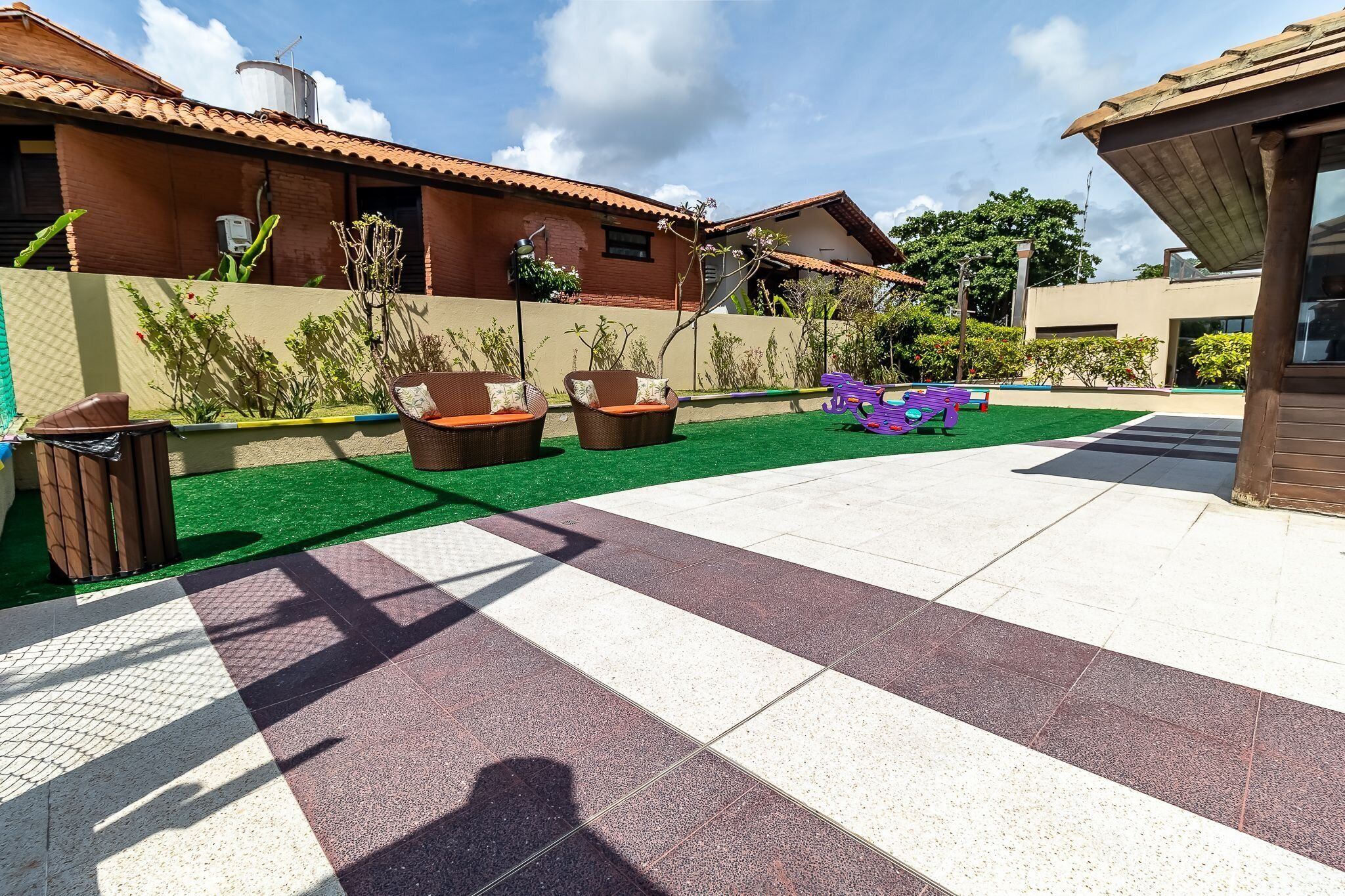 A patio with outdoor furniture, a green artificial turf area, and a tiled walkway.