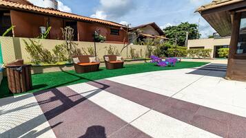 A patio with outdoor furniture, a green artificial turf area, and a tiled walkway.