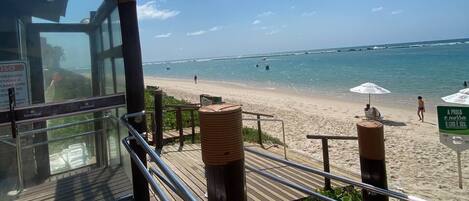 A wooden deck with metal railings overlooking a beach.