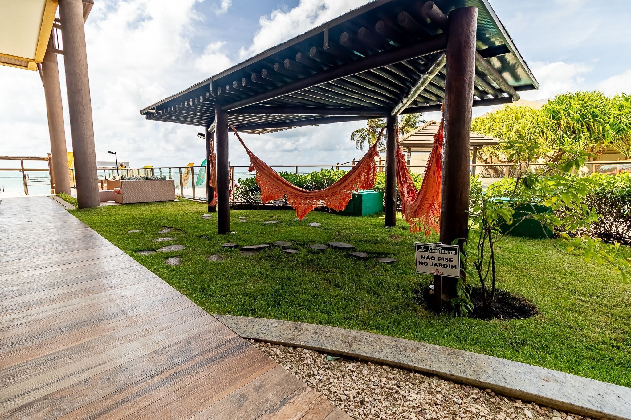 A covered outdoor area with a hammock, a wooden deck, and a sign indicating a garden area.