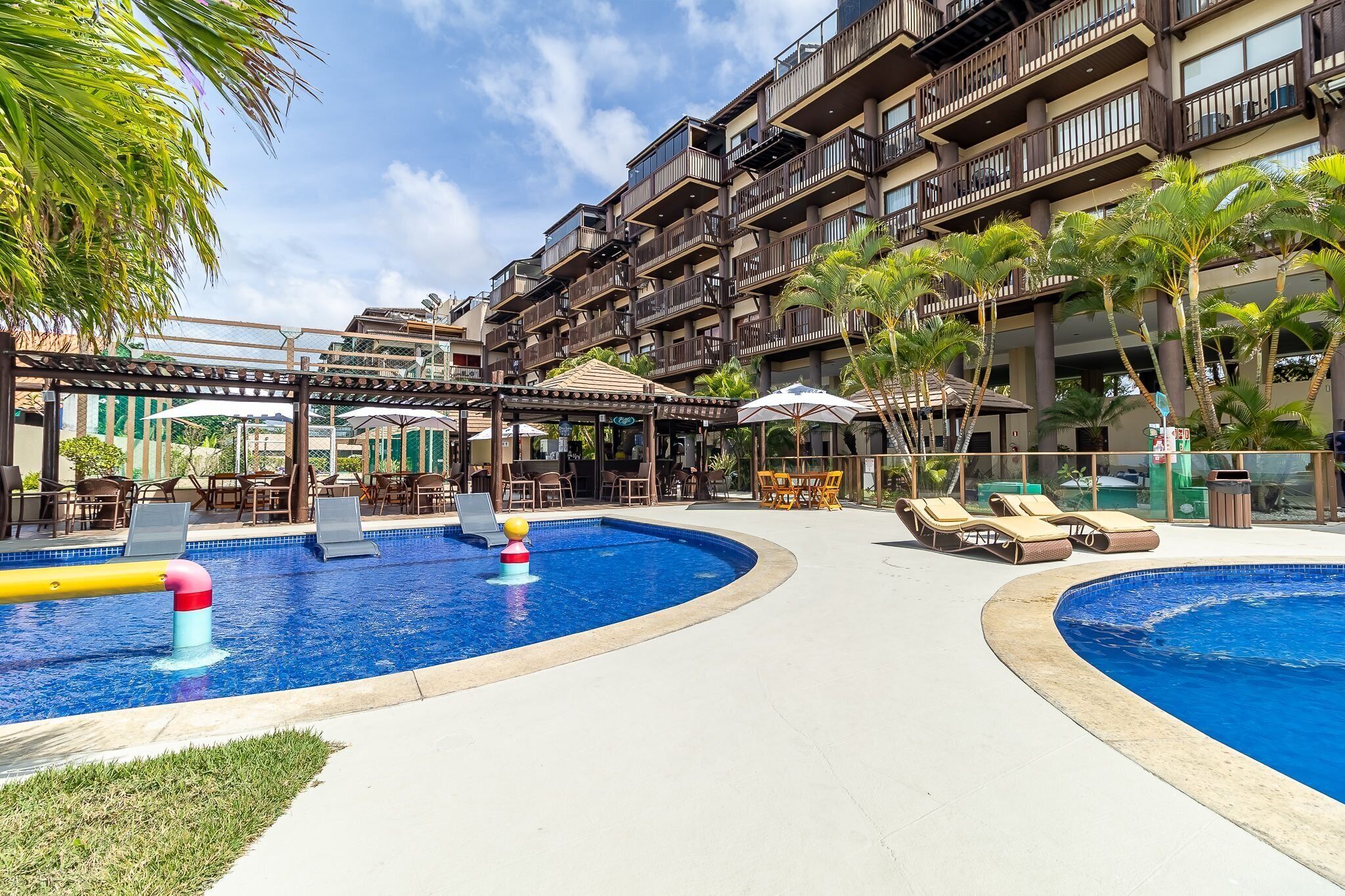 A hotel with a swimming pool, outdoor seating, and a covered area.