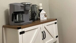 Una encimera de cocina con una cafetera, una taza y un cartel decorativo que dice 'Café' y 'hogar'.