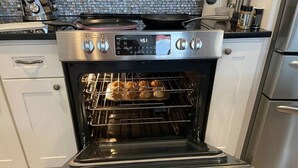 Un horno con pantalla digital, una rejilla con productos horneados y una campana extractora de acero inoxidable encima.